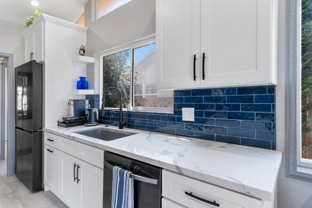 Stylish kitchen in Frisco, TX, showcasing white cabinets, a deep blue tile backsplash, and updated appliances