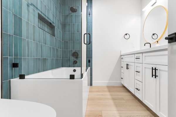 A frameless glass shower with geometric green tile and built-in bench highlights this bathroom remodel in Allen, TX.